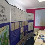 Photograph of exhibition banners and table of resources with map of the Scottish Highlands and Islands in the background